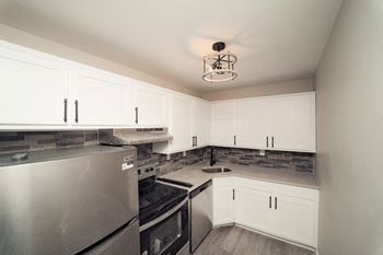 a kitchen with white cabinets and a stainless steel refrigerator